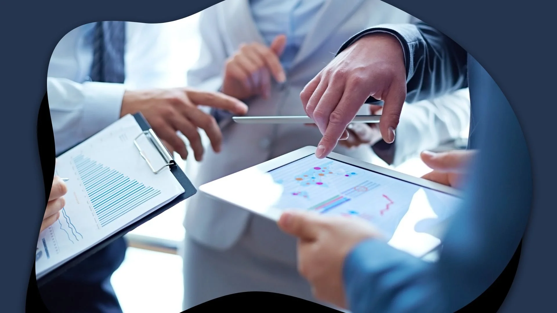 A group of professionals discussing data and charts on digital devices and clipboards in a business setting.