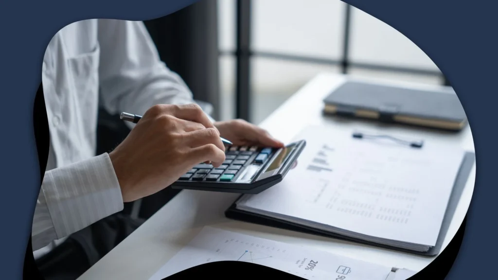 Professional reviewing financial documents while using a calculator at a desk, conveying careful analysis, planning, and business decision-making.